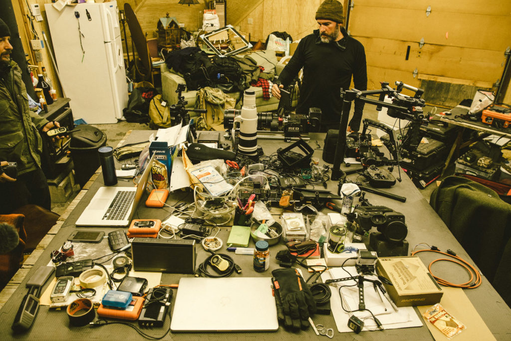 a tabletop full of filmmaking equipment like cameras, lenses, cables, etc